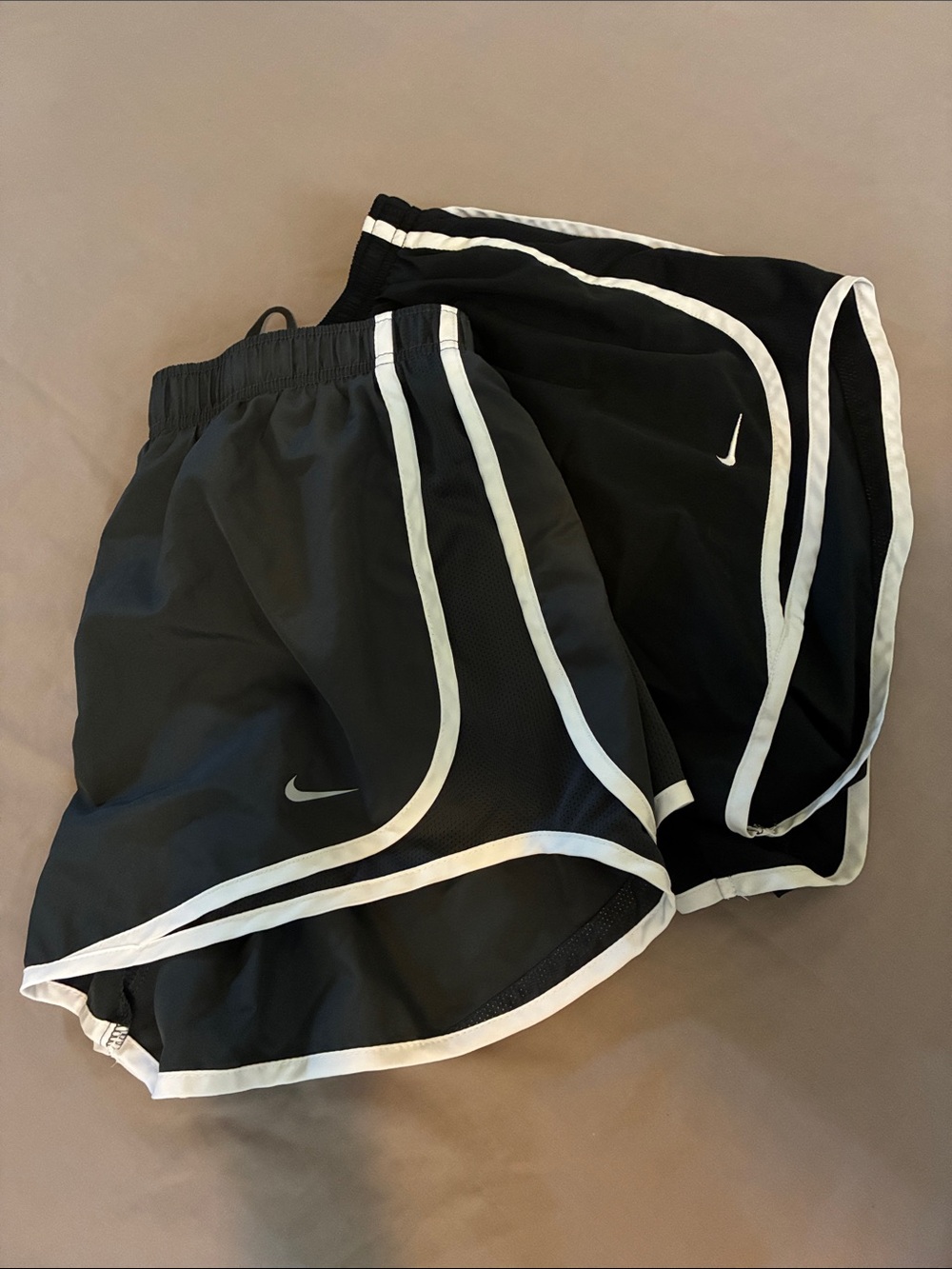 Two pairs of Nike athletic shorts, one dark gray, one black